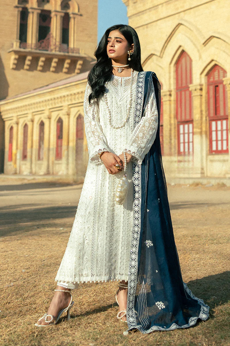 Model wearing Mushq Saugaat City of Lights Roshni in white with navy dupatta and lace details. Shop Pakistani luxury pret online in the UK.