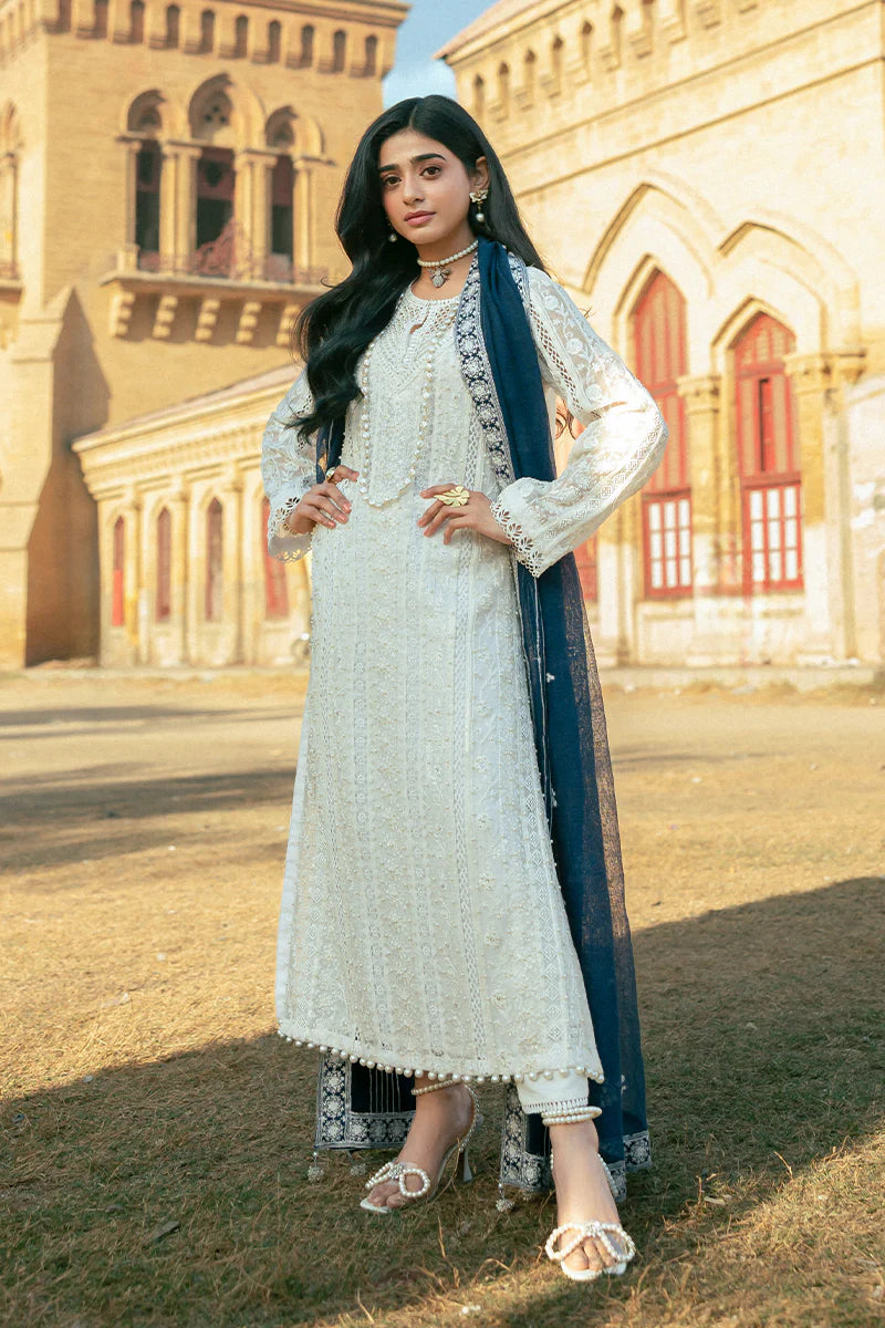 Model wearing Mushq Saugaat City of Lights Roshni in white with navy dupatta and lace details. Shop Pakistani luxury pret online in the UK.