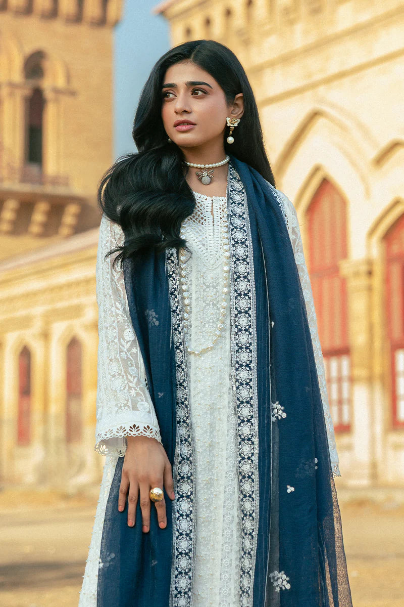 Model wearing Mushq Saugaat City of Lights Roshni in white with navy dupatta and lace details. Shop Pakistani luxury pret online in the UK.