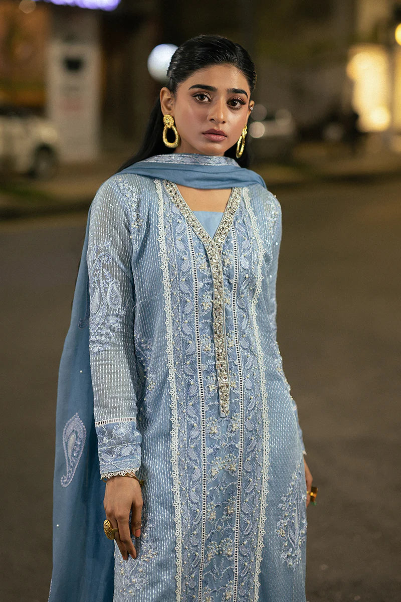 Model wearing Mushq Saugaat City of Lights Umeed in pastel blue with intricate embellishments. Shop Pakistani luxury pret online in the UK.