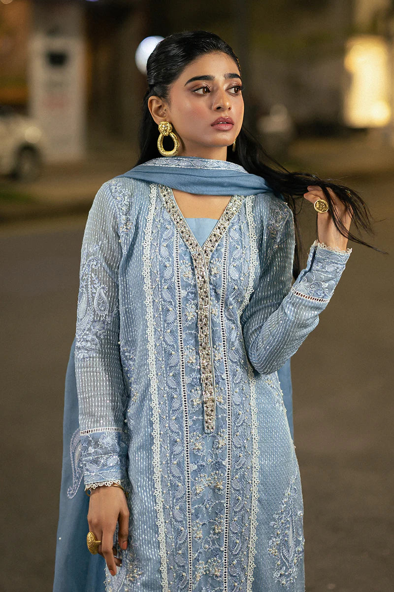 Model wearing Mushq Saugaat City of Lights Umeed in pastel blue with intricate embellishments. Shop Pakistani luxury pret online in the UK.