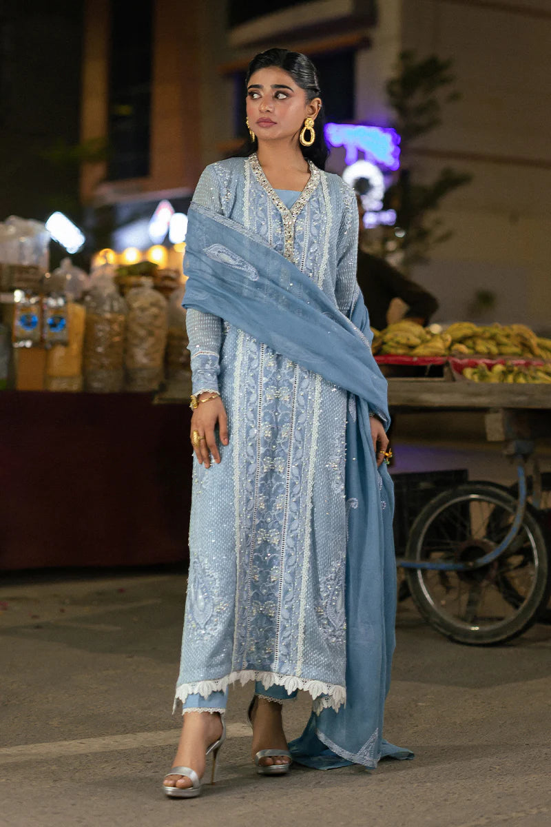 Model wearing Mushq Saugaat City of Lights Umeed in pastel blue with intricate embellishments. Shop Pakistani luxury pret online in the UK.