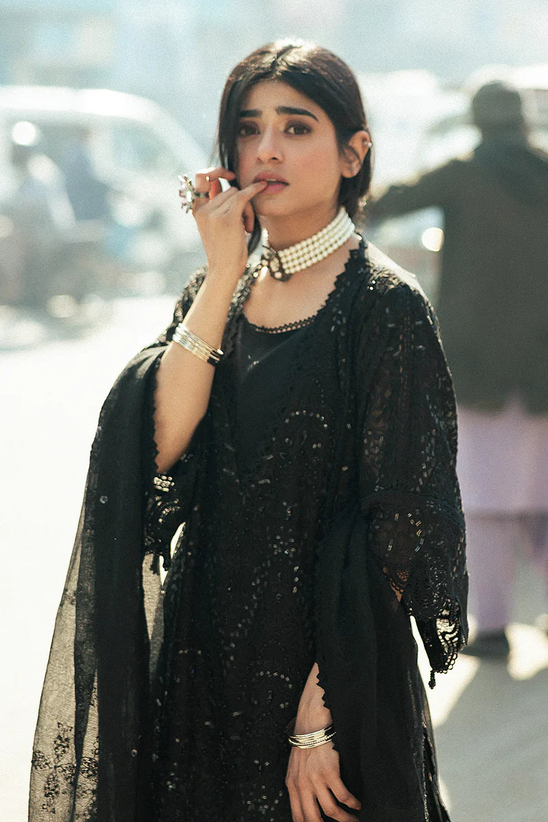 Model wearing Mushq Saugaat City of Lights Rija in black with intricate embellishments. Shop Pakistani luxury pret online in the UK.