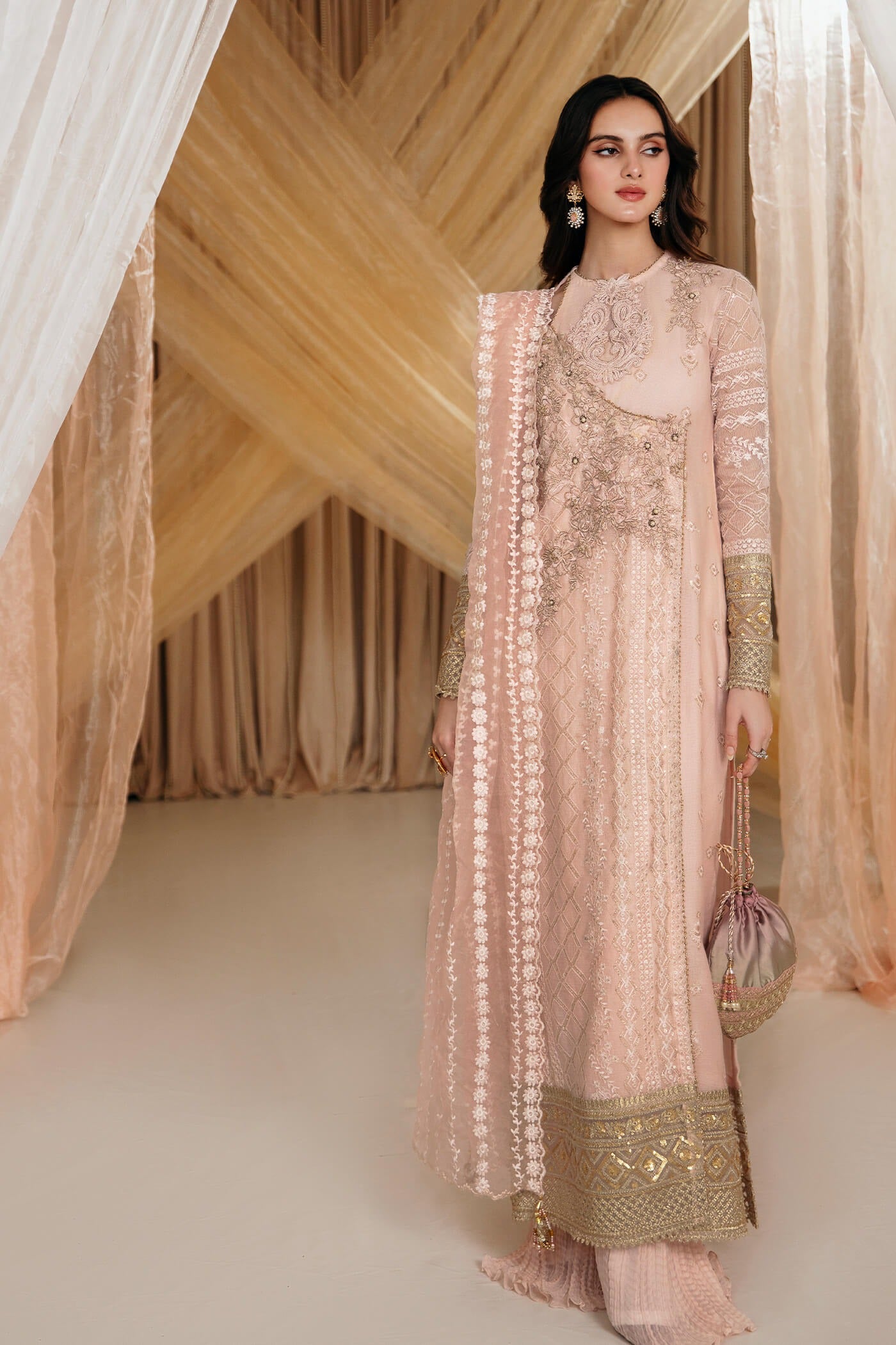 Model wearing Faiza Saqlain's Rose dress from the Musferah Saad Mystere Eid Collection '24. A soft pink Pakistani Eid dress with intricate gold embroidery, perfect for Pakistani designer clothes shoppers in the UK.