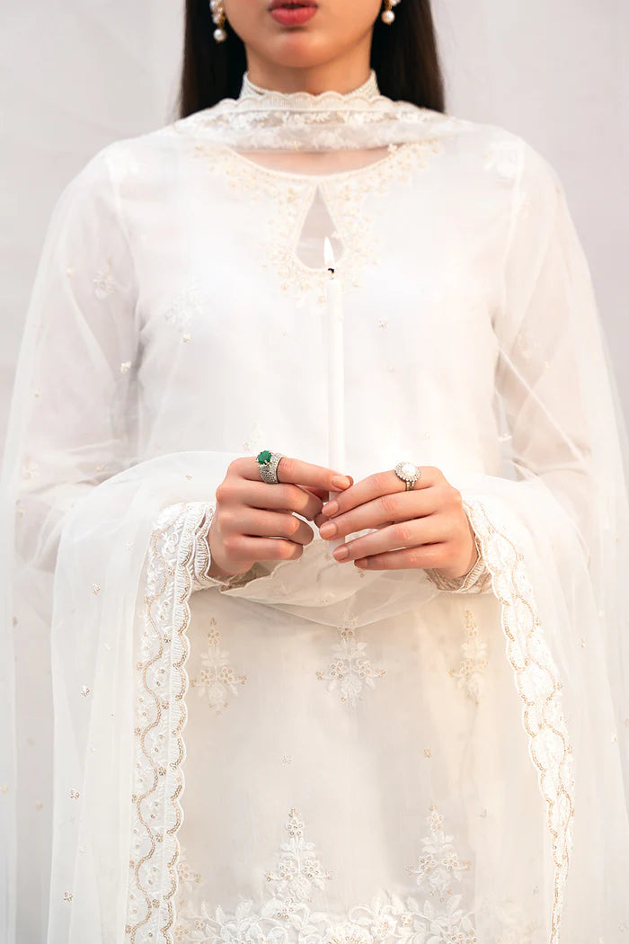 Model wearing Saira Rizwan Amaya dress, elegant white Pakistani clothes UK, detailed Eid wear.