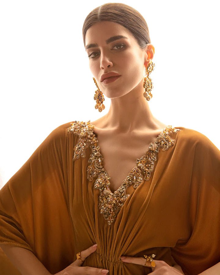 Model wearing a golden Altin dress from Faiza Saqlain's Aleira Evening Edit '24 collection. Pakistani clothes online in UK.