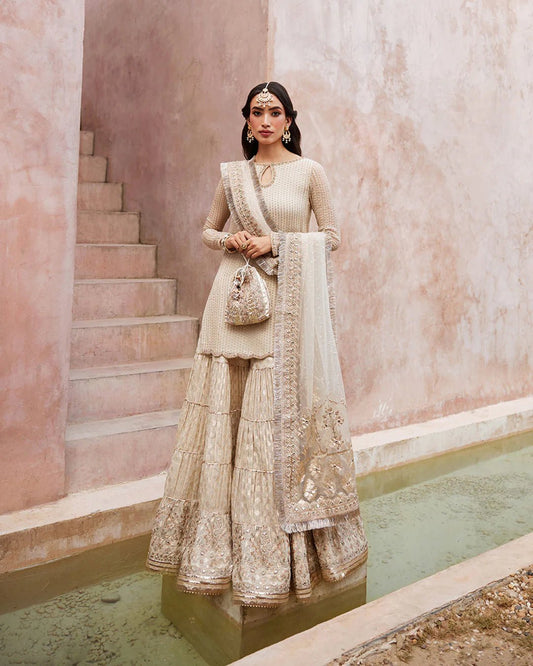 Model wearing a cream-colored Kaia dress from Faiza Saqlain's Lenora Luxury Pret '24 collection. Pakistani clothes online in UK.