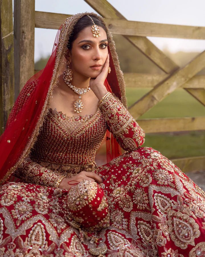 Model wearing a red Raeni bridal dress by Faiza Saqlain adorned with gold embroidery, perfect for Pakistani weddings, available online in the UK.