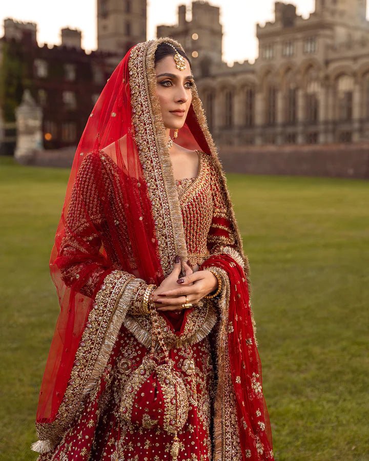 Model wearing a red Raeni bridal dress by Faiza Saqlain adorned with gold embroidery, perfect for Pakistani weddings, available online in the UK.