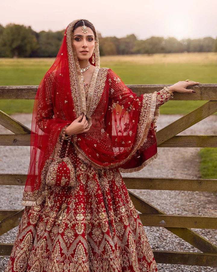 Model wearing a red Raeni bridal dress by Faiza Saqlain adorned with gold embroidery, perfect for Pakistani weddings, available online in the UK.