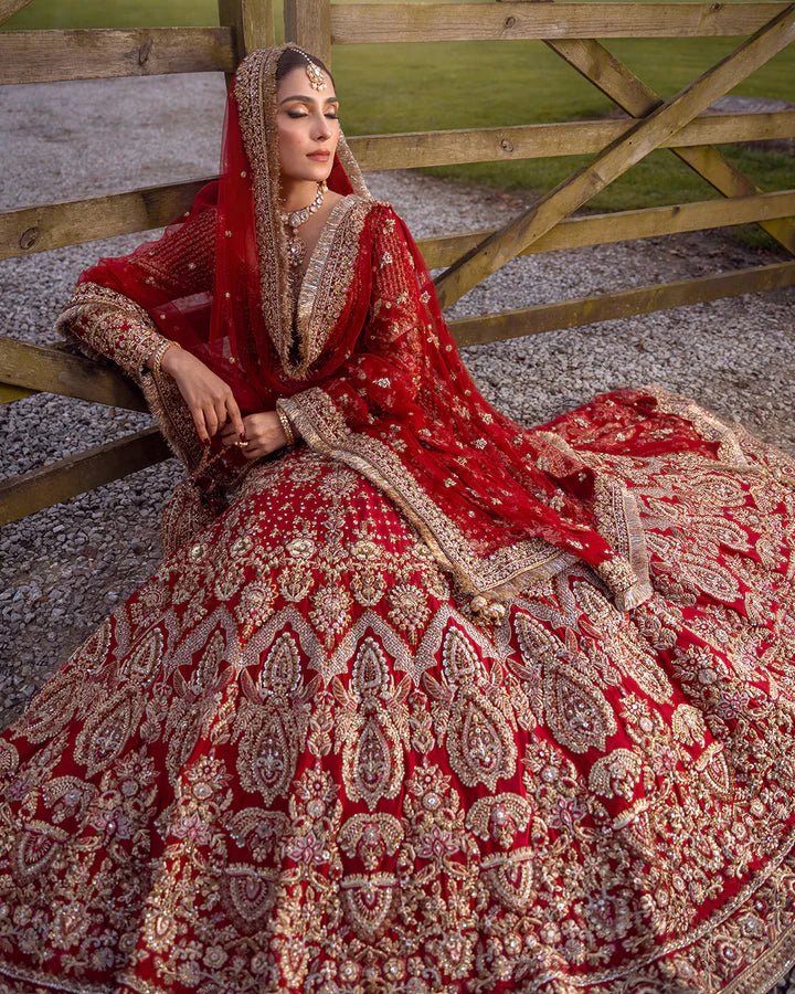 Model wearing a red Raeni bridal dress by Faiza Saqlain adorned with gold embroidery, perfect for Pakistani weddings, available online in the UK.