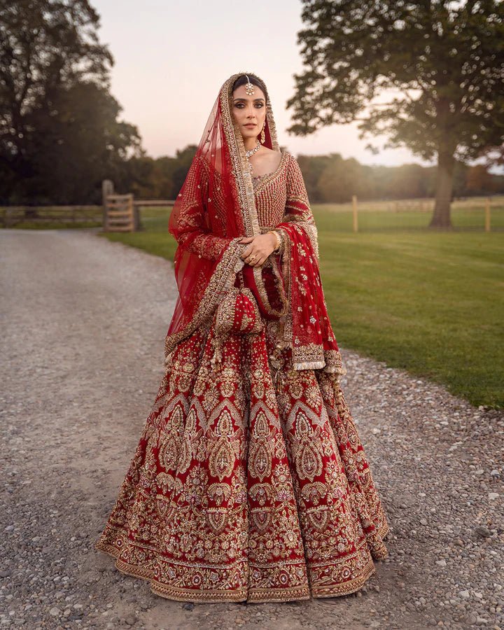 Model wearing a red Raeni bridal dress by Faiza Saqlain adorned with gold embroidery, perfect for Pakistani weddings, available online in the UK.