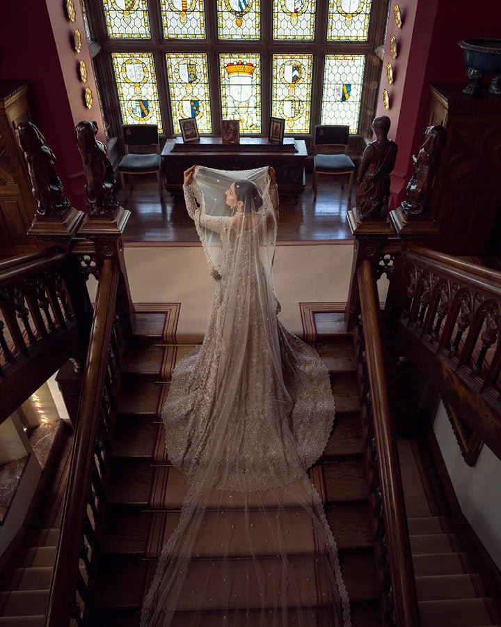 Model wearing an elegant off - white Reem bridal dress by Faiza Saqlain, featuring intricate beadwork, perfect for Pakistani weddings, available online in the UK.