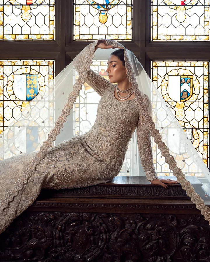 Model wearing an elegant off - white Reem bridal dress by Faiza Saqlain, featuring intricate beadwork, perfect for Pakistani weddings, available online in the UK.