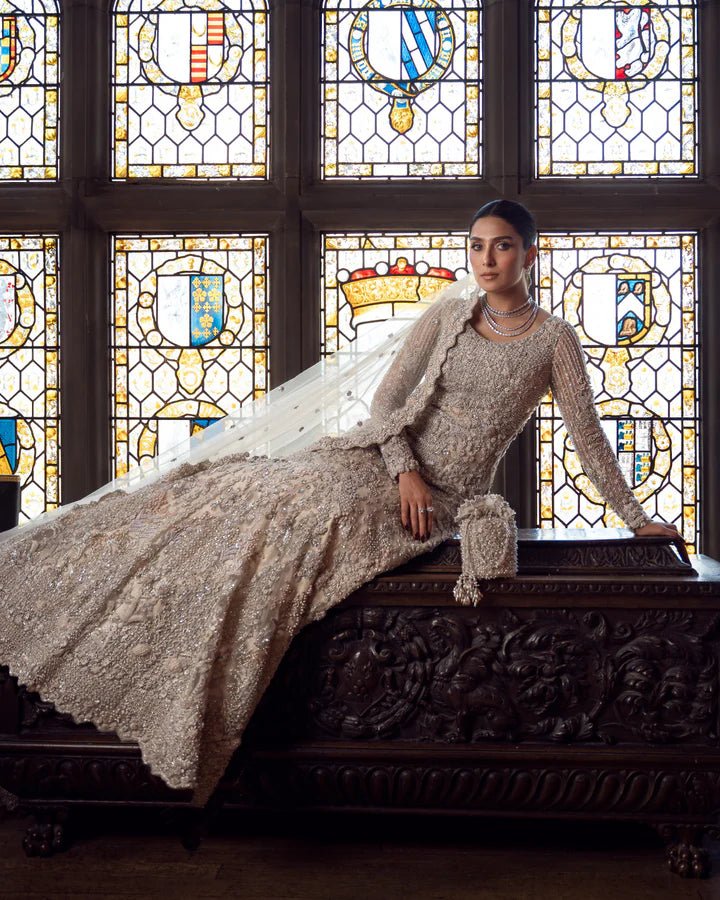 Model wearing an elegant off - white Reem bridal dress by Faiza Saqlain, featuring intricate beadwork, perfect for Pakistani weddings, available online in the UK.