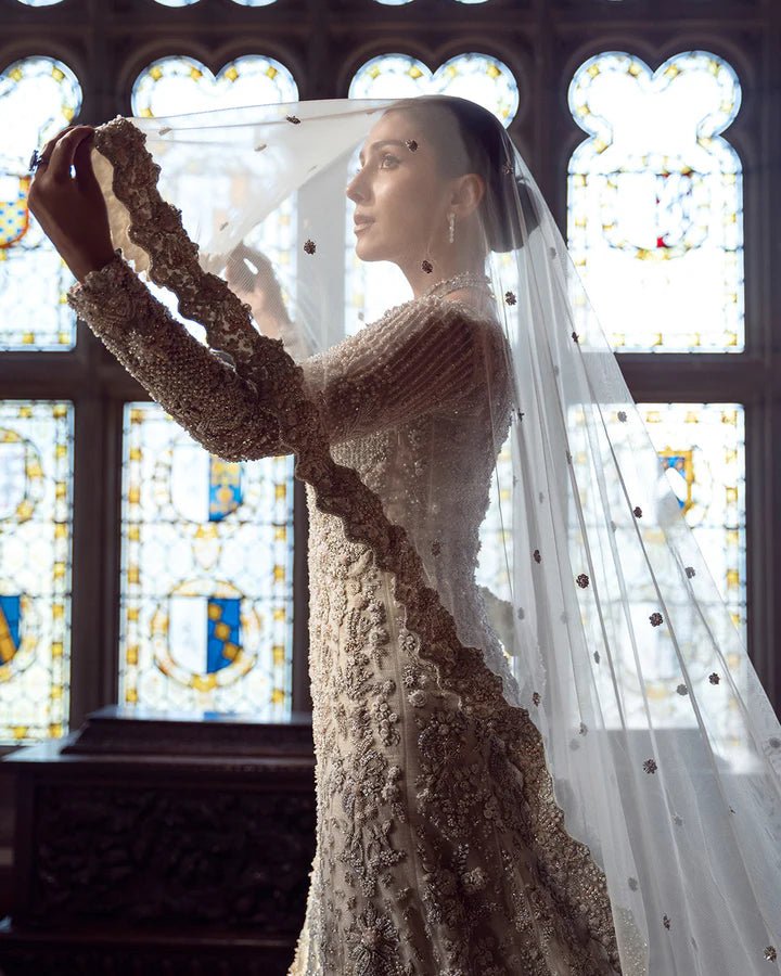 Model wearing an elegant off - white Reem bridal dress by Faiza Saqlain, featuring intricate beadwork, perfect for Pakistani weddings, available online in the UK.