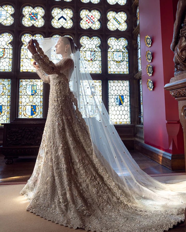 Model wearing an elegant off - white Reem bridal dress by Faiza Saqlain, featuring intricate beadwork, perfect for Pakistani weddings, available online in the UK.