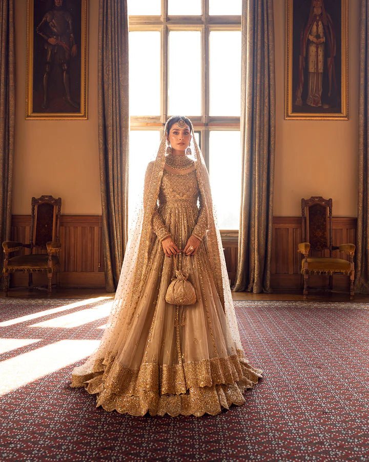 Model wearing a gold Zariana bridal dress by Faiza Saqlain, featuring intricate embellishments, perfect for Pakistani weddings, available online in the UK.