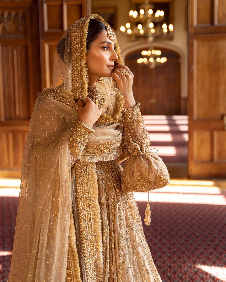 Model wearing a gold Zariana bridal dress by Faiza Saqlain, featuring intricate embellishments, perfect for Pakistani weddings, available online in the UK.