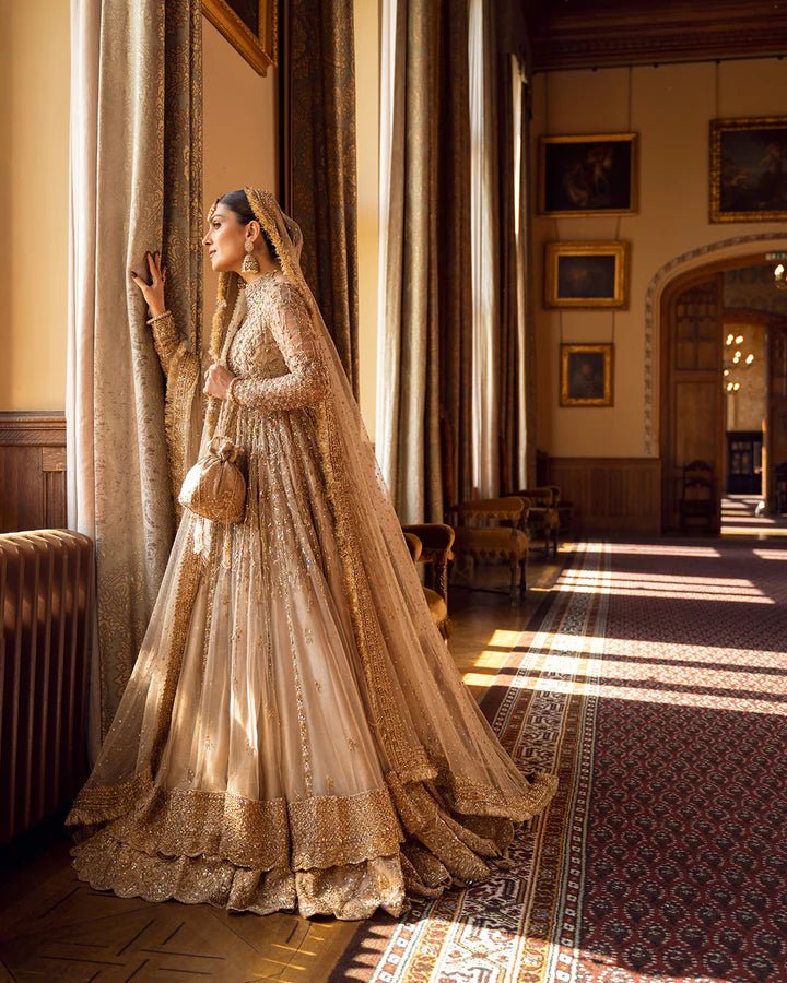 Model wearing a gold Zariana bridal dress by Faiza Saqlain, featuring intricate embellishments, perfect for Pakistani weddings, available online in the UK.