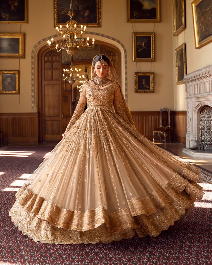 Model wearing a gold Zariana bridal dress by Faiza Saqlain, featuring intricate embellishments, perfect for Pakistani weddings, available online in the UK.