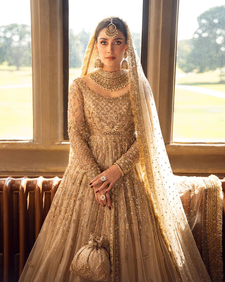 Model wearing a gold Zariana bridal dress by Faiza Saqlain, featuring intricate embellishments, perfect for Pakistani weddings, available online in the UK.