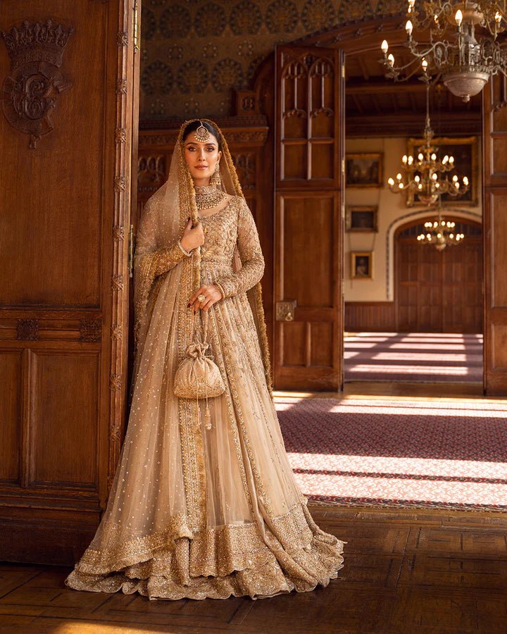 Model wearing a gold Zariana bridal dress by Faiza Saqlain, featuring intricate embellishments, perfect for Pakistani weddings, available online in the UK.