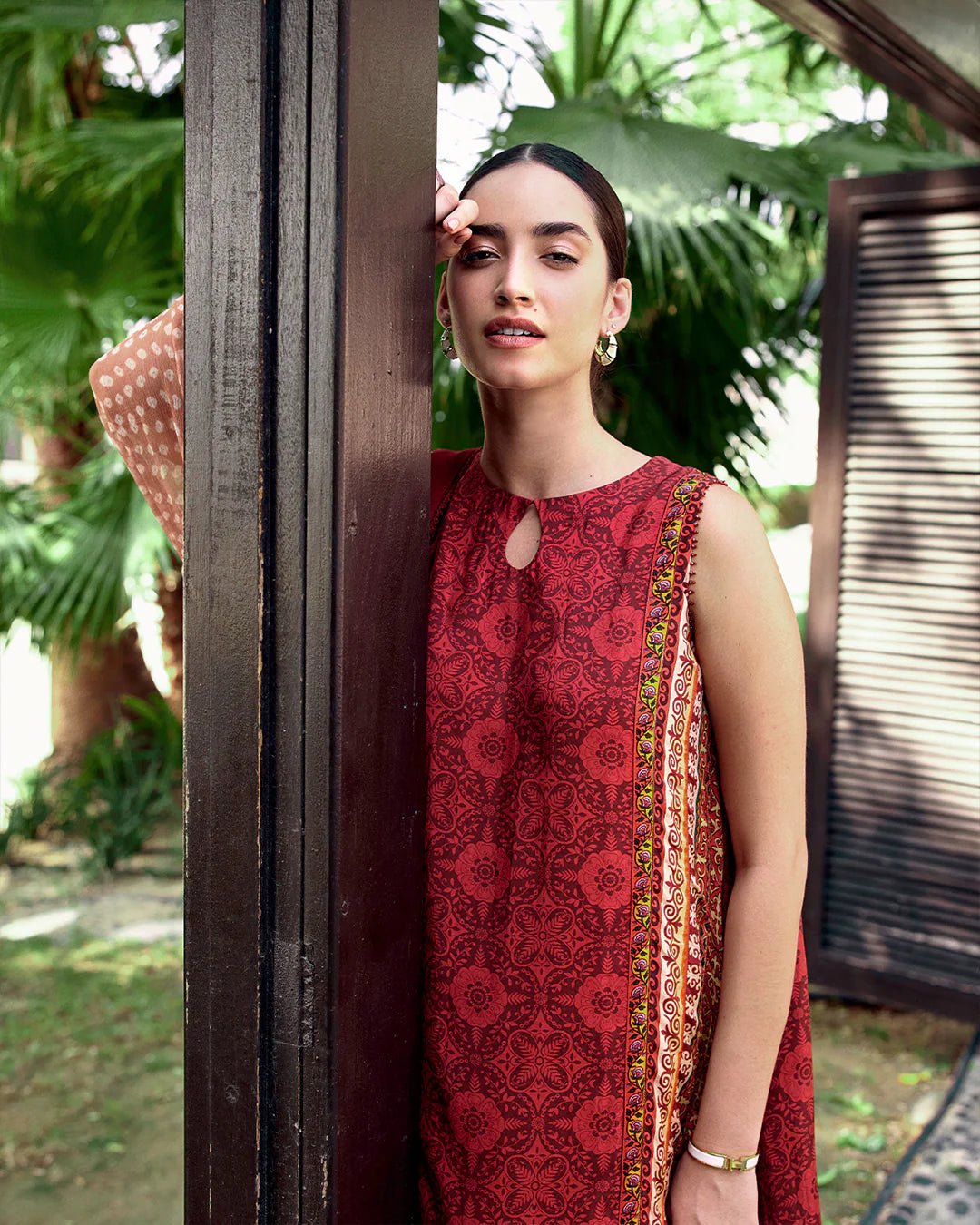 Model wearing Faiza Saqlain Carmela Gloriana dress in rich red with intricate patterns and a vibrant printed dupatta. Shop Pakistani bridal dresses online in the UK now.