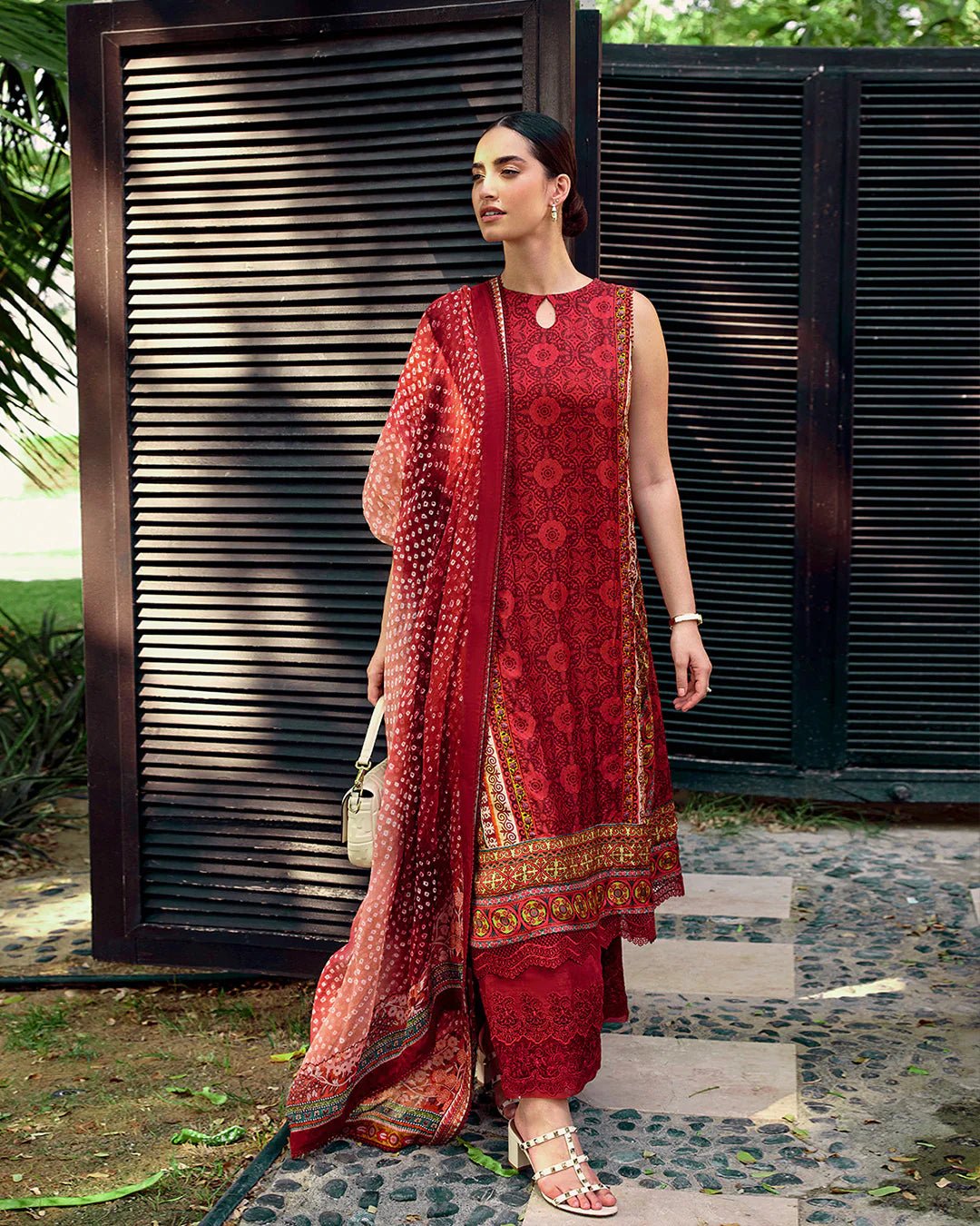 Model wearing Faiza Saqlain Carmela Gloriana dress in rich red with intricate patterns and a vibrant printed dupatta. Shop Pakistani bridal dresses online in the UK now.