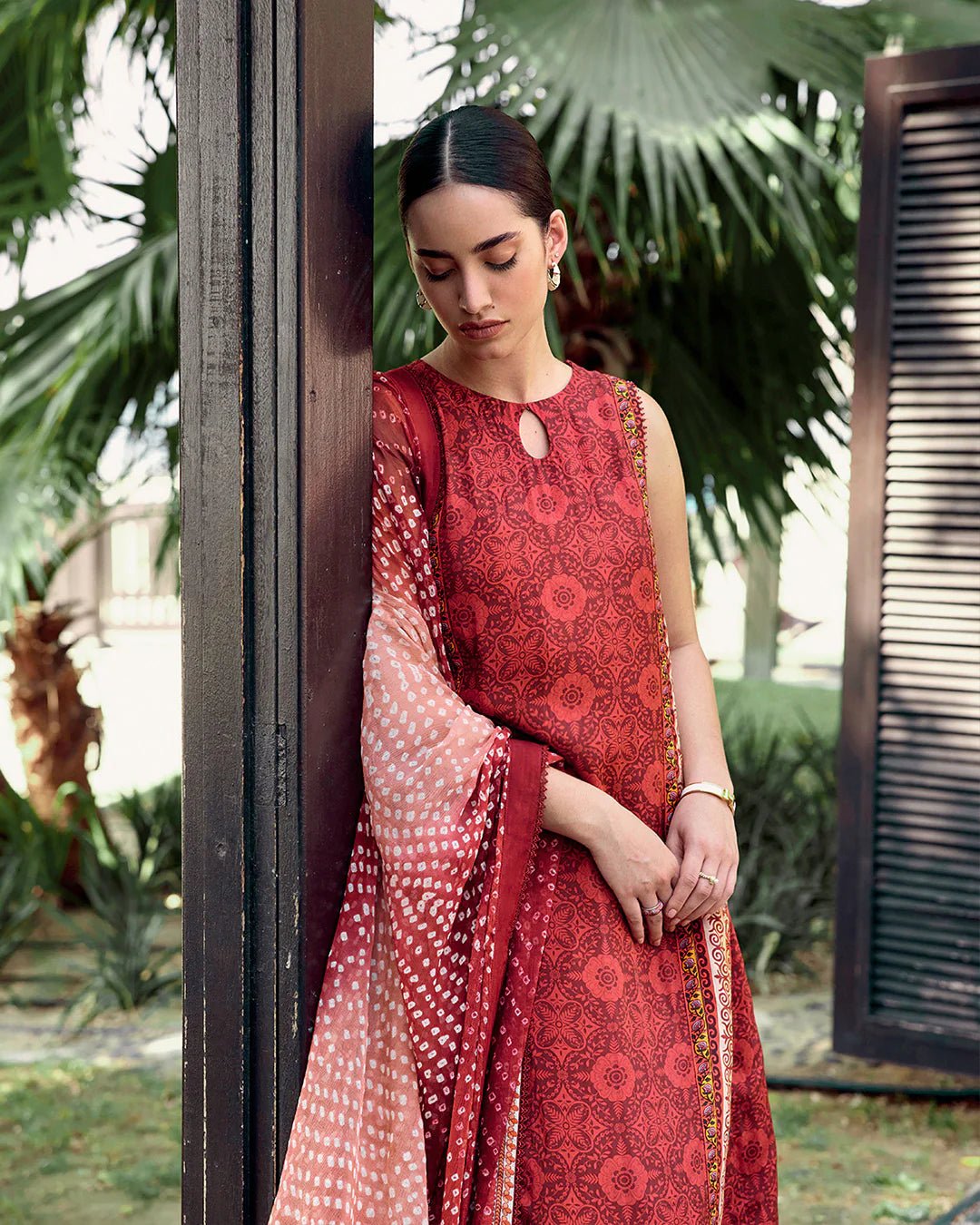 Model wearing Faiza Saqlain Carmela Gloriana dress in rich red with intricate patterns and a vibrant printed dupatta. Shop Pakistani bridal dresses online in the UK now.