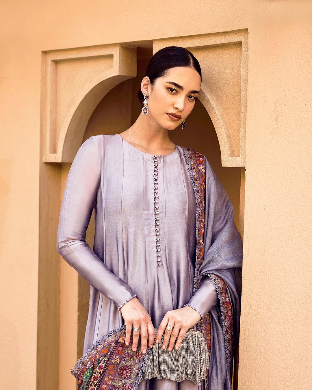 Model wearing Faiza Saqlain Carmela Mersera dress in mauve grey with intricate embroidery and a vibrant printed dupatta. Shop Pakistani bridal dresses online in the UK now.