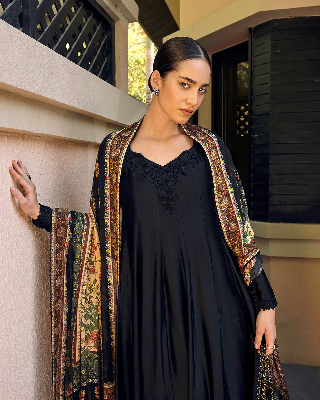 Model wearing Faiza Saqlain Carmela Shelina dress in black with intricate detailing and a vibrant printed shawl. Shop Pakistani bridal dresses online in the UK now.