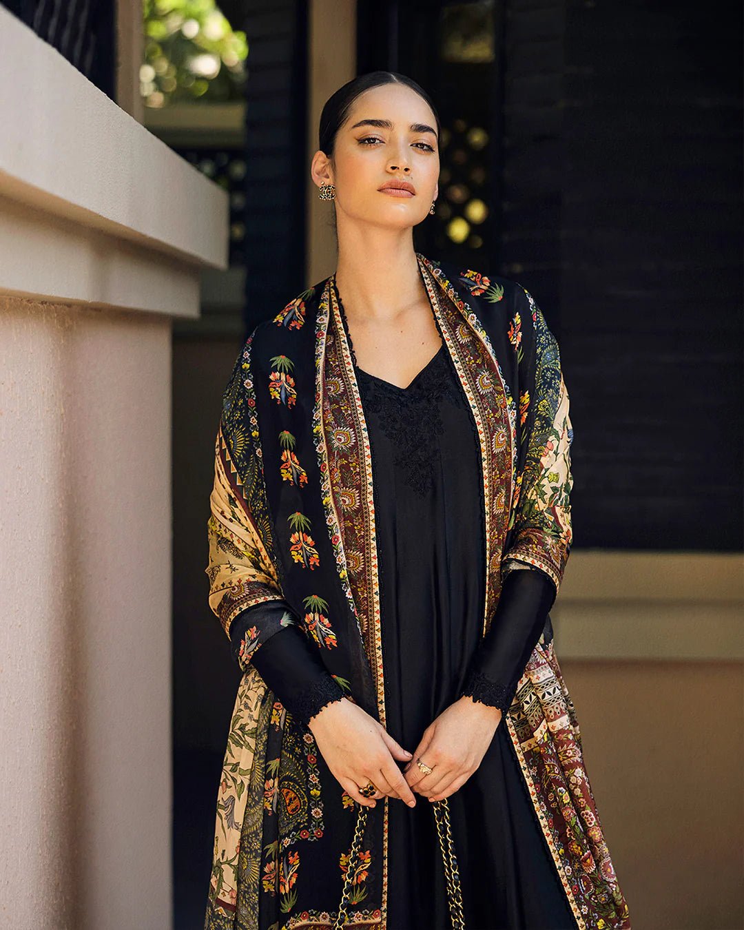 Model wearing Faiza Saqlain Carmela Shelina dress in black with intricate detailing and a vibrant printed shawl. Shop Pakistani bridal dresses online in the UK now.