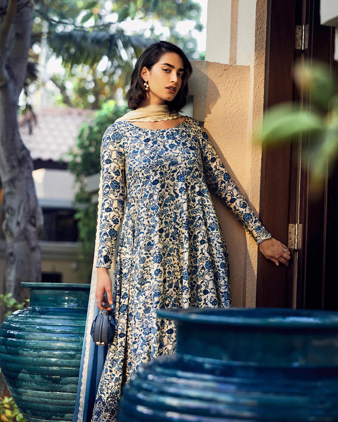 Model wearing Faiza Saqlain Carmela Terylin dress in blue and cream with intricate floral prints. Shop Pakistani bridal dresses online in the UK now.