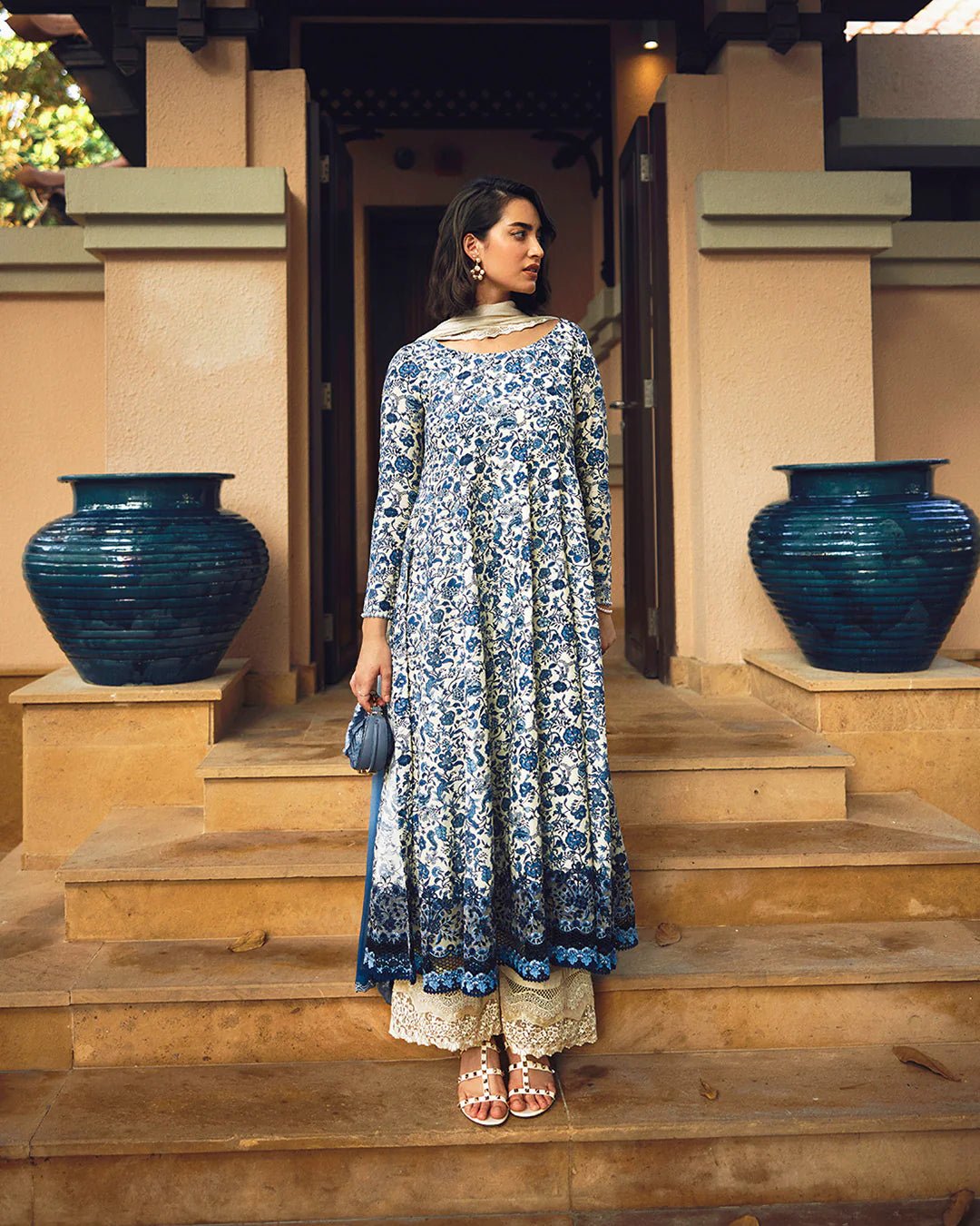 Model wearing Faiza Saqlain Carmela Terylin dress in blue and cream with intricate floral prints. Shop Pakistani bridal dresses online in the UK now.