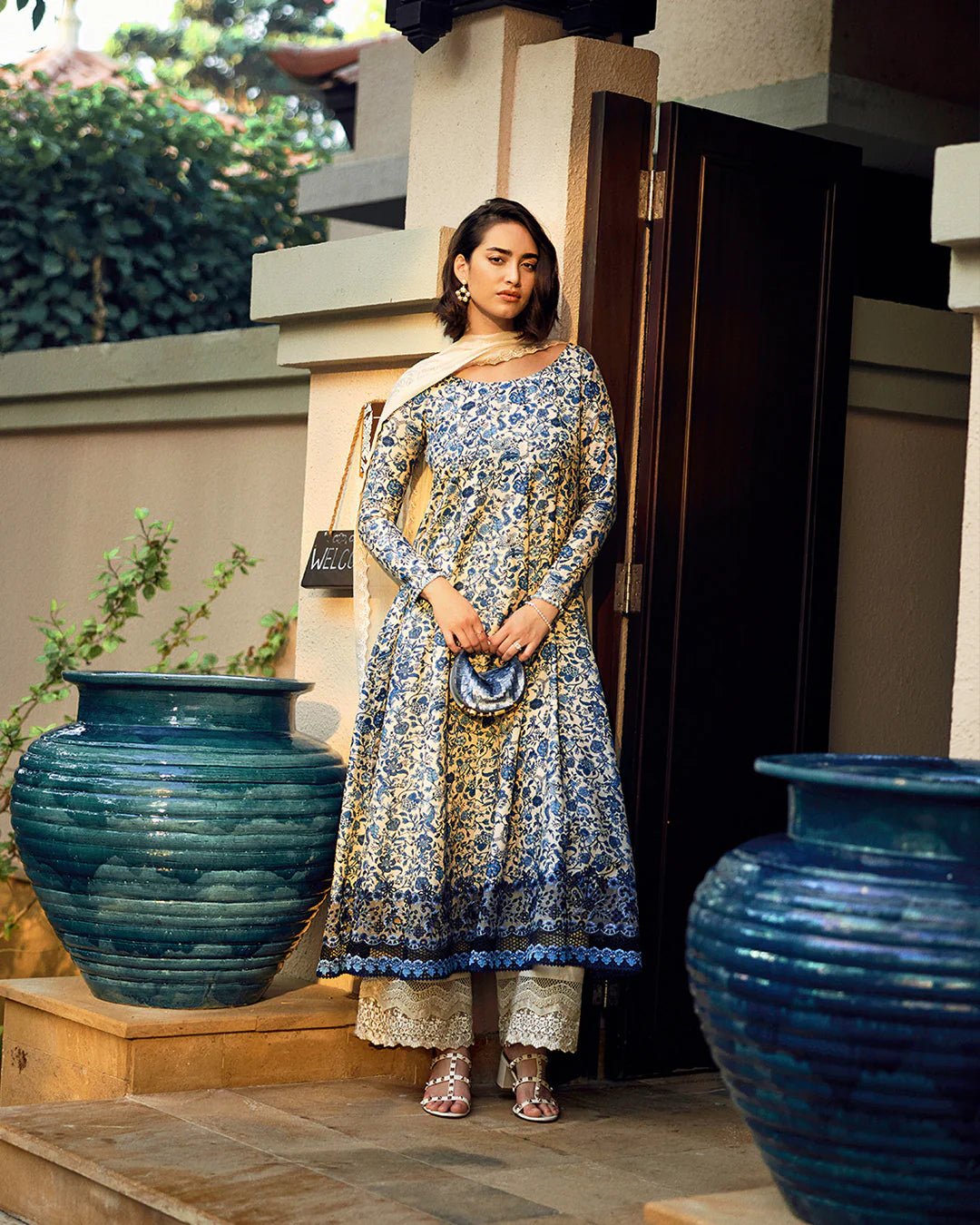 Model wearing Faiza Saqlain Carmela Terylin dress in blue and cream with intricate floral prints. Shop Pakistani bridal dresses online in the UK now.