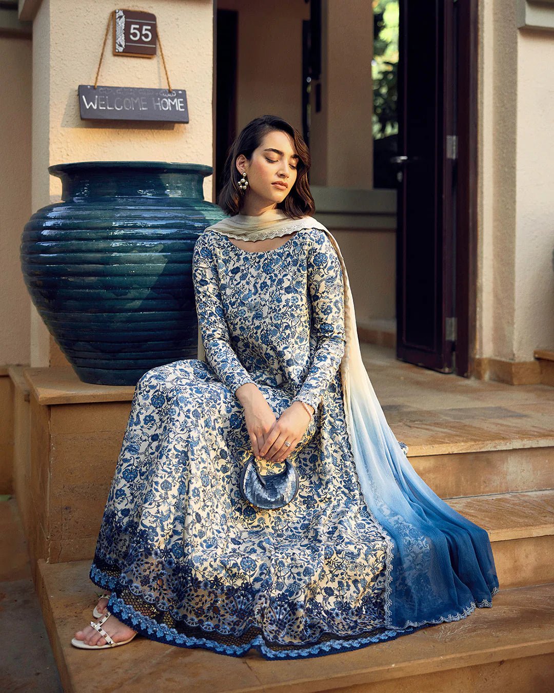 Model wearing Faiza Saqlain Carmela Terylin dress in blue and cream with intricate floral prints. Shop Pakistani bridal dresses online in the UK now.