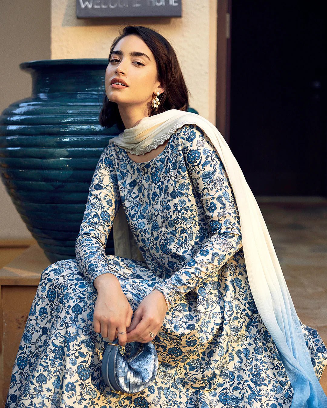 Model wearing Faiza Saqlain Carmela Terylin dress in blue and cream with intricate floral prints. Shop Pakistani bridal dresses online in the UK now.