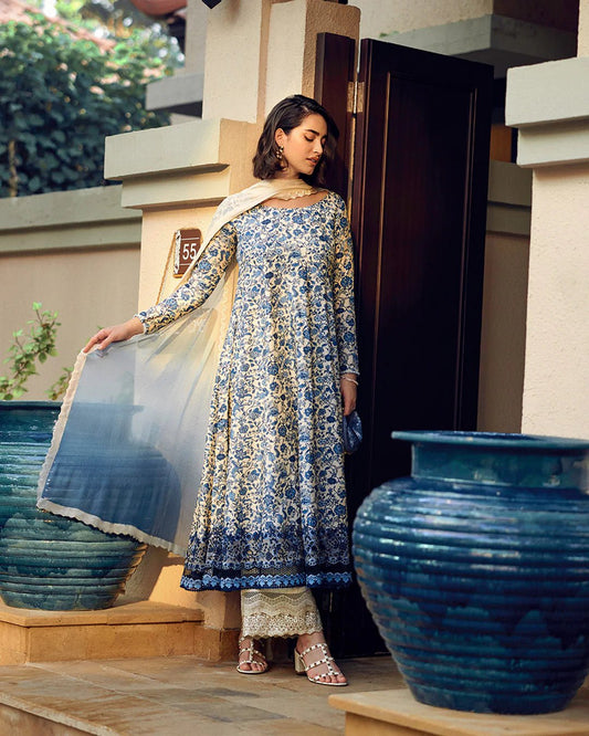 Model wearing Faiza Saqlain Carmela Terylin dress in blue and cream with intricate floral prints. Shop Pakistani bridal dresses online in the UK now.