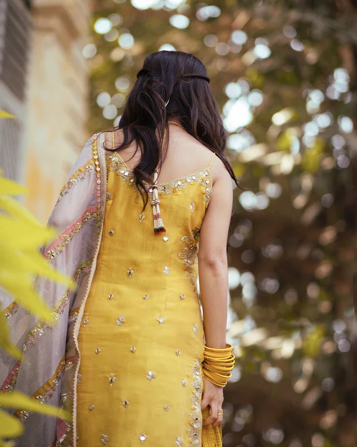 Model wearing Faiza Saqlain Fara dress in yellow mehndi dress from the Dhoop Kinaray Formals collection, ideal for weddings, available for Pakistani clothes online in the UK.