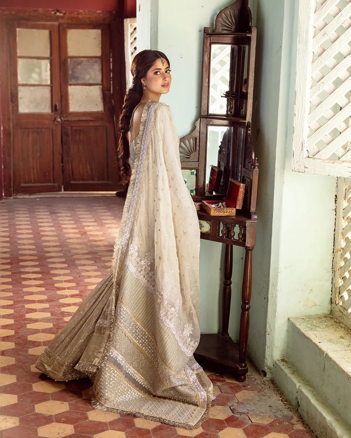 Model wearing Faiza Saqlain MINHA dress in ivory from the Dhoop Kinaray Formals collection, perfect for Pakistani weddings and formals, available online in the UK.