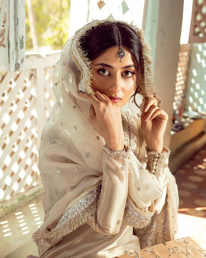 Model wearing Faiza Saqlain MINHA dress in ivory from the Dhoop Kinaray Formals collection, perfect for Pakistani weddings and formals, available online in the UK.