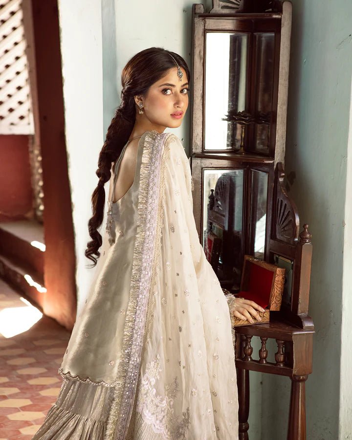 Model wearing Faiza Saqlain MINHA dress in ivory from the Dhoop Kinaray Formals collection, perfect for Pakistani weddings and formals, available online in the UK.