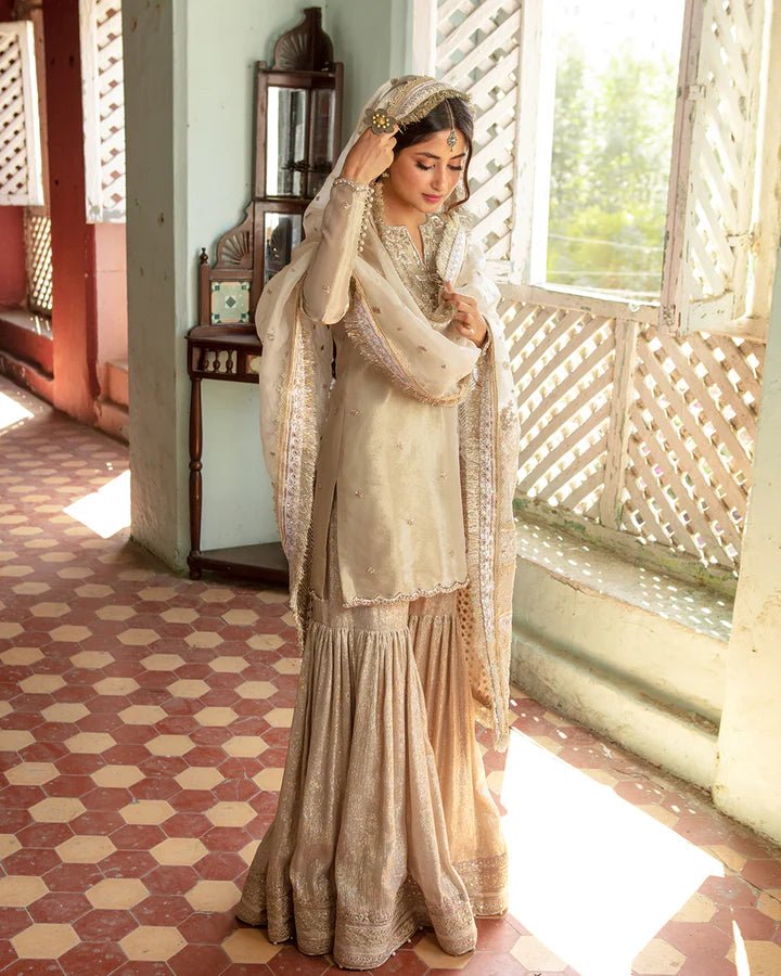 Model wearing Faiza Saqlain MINHA dress in ivory from the Dhoop Kinaray Formals collection, perfect for Pakistani weddings and formals, available online in the UK.