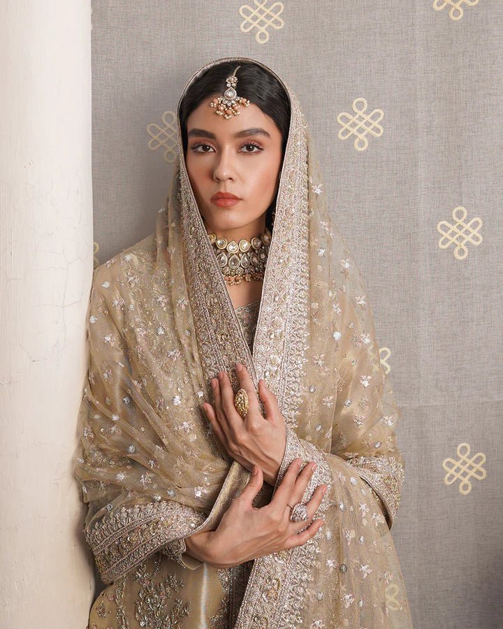 Model wearing Faiza Saqlain Formals Irina Aurela dress in Dull Gold, Pakistani clothes online in UK.