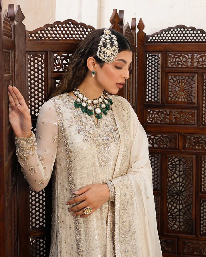 Model wearing a cream Elvana dress with intricate embellishments from Faiza Saqlain's Aleira Evening Edit '24 collection. Pakistani clothes online in UK.