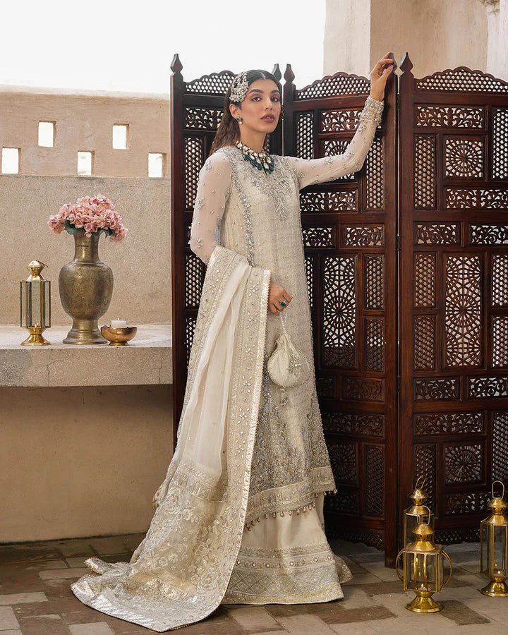 Model wearing a cream Elvana dress with intricate embellishments from Faiza Saqlain's Aleira Evening Edit '24 collection. Pakistani clothes online in UK.