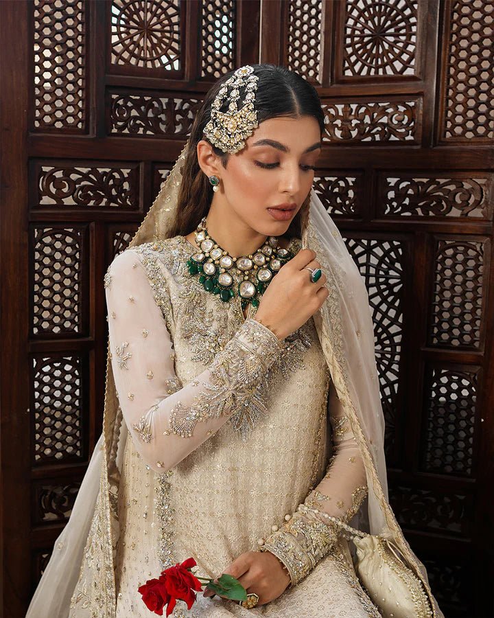 Model wearing a cream Elvana dress with intricate embellishments from Faiza Saqlain's Aleira Evening Edit '24 collection. Pakistani clothes online in UK.