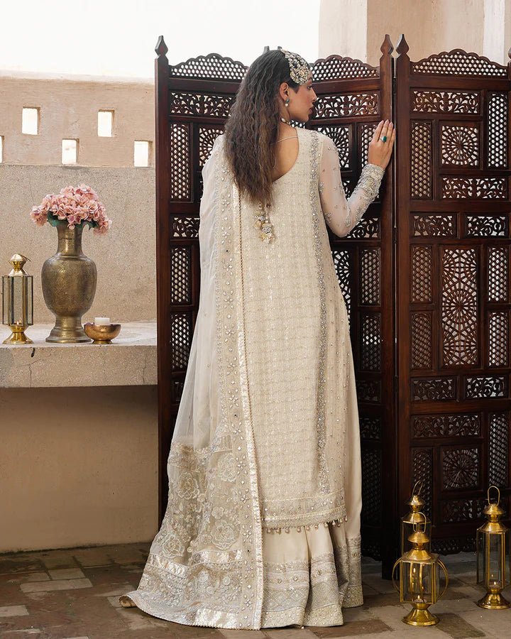 Model wearing a cream Elvana dress with intricate embellishments from Faiza Saqlain's Aleira Evening Edit '24 collection. Pakistani clothes online in UK.