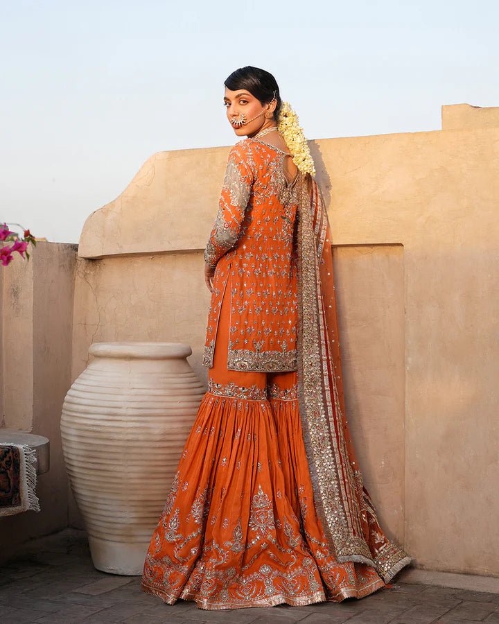 Model wearing Faiza Saqlain Formals Irina Oct '23 Sevgi dress in orange gold, Pakistani clothes online in UK.